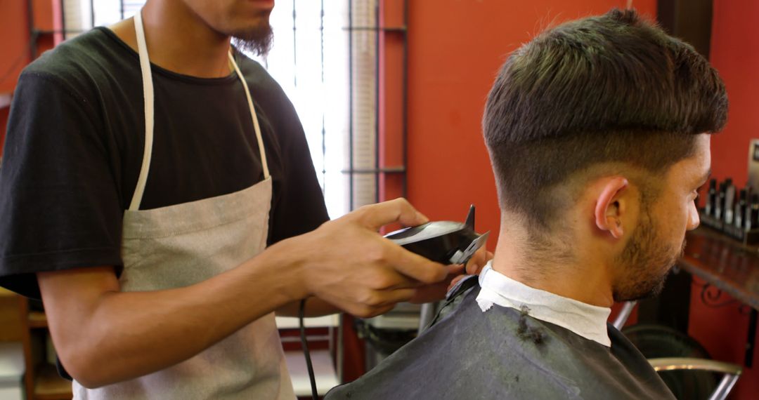 Barber Wearing Apron Trimming Man's Hair in Barbershop - Free Images, Stock Photos and Pictures on Pikwizard.com