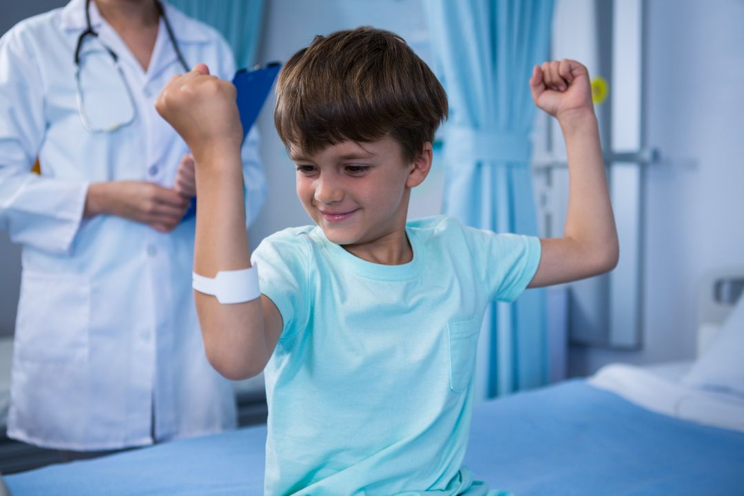 Boy flexing his muscles and female doctor standing in background - Free Images, Stock Photos and Pictures on Pikwizard.com
