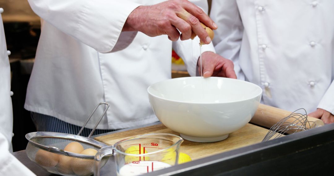 Professional chefs cracking egg into bowl in commercial kitchen - Free Images, Stock Photos and Pictures on Pikwizard.com