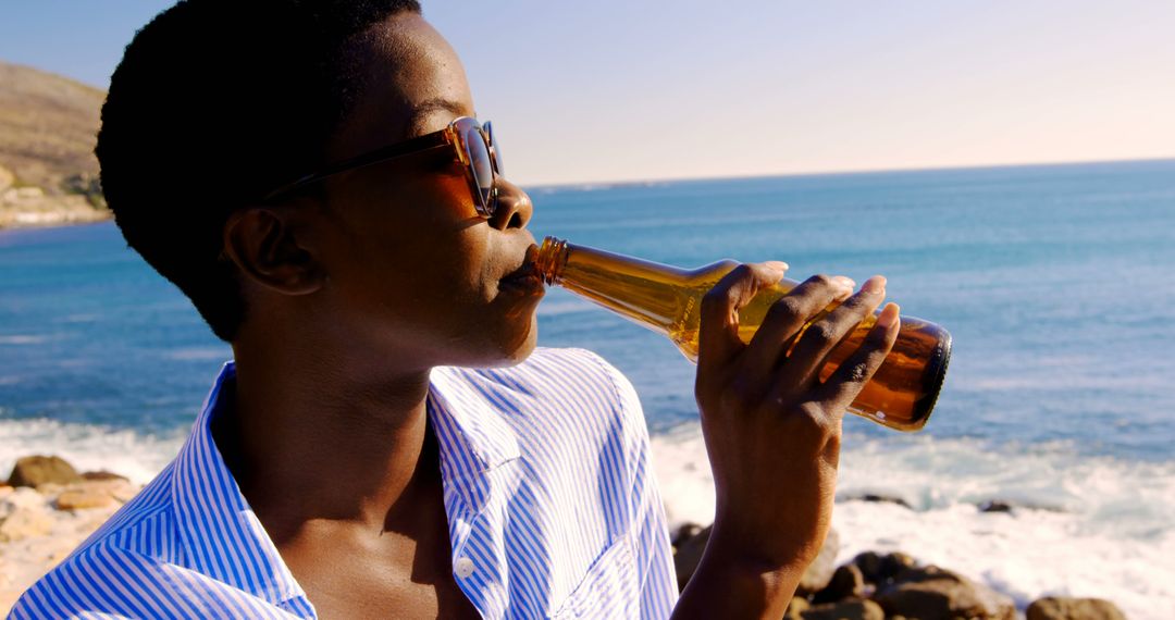 Young man enjoying cold beer by seaside on a sunny day - Free Images, Stock Photos and Pictures on Pikwizard.com