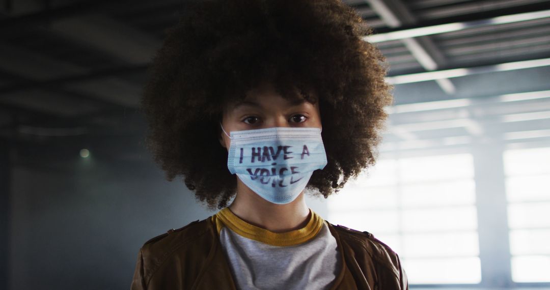 Young Activist Wearing Mask with Message in Industrial Building - Free Images, Stock Photos and Pictures on Pikwizard.com