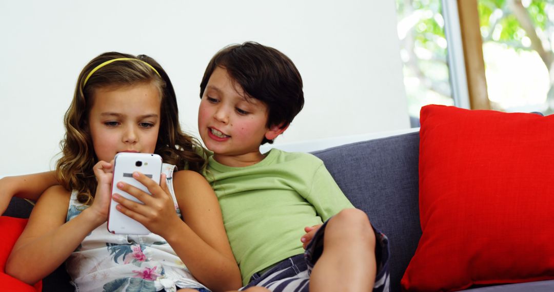 Young Children Using Smartphone Together on Cozy Couch - Free Images, Stock Photos and Pictures on Pikwizard.com