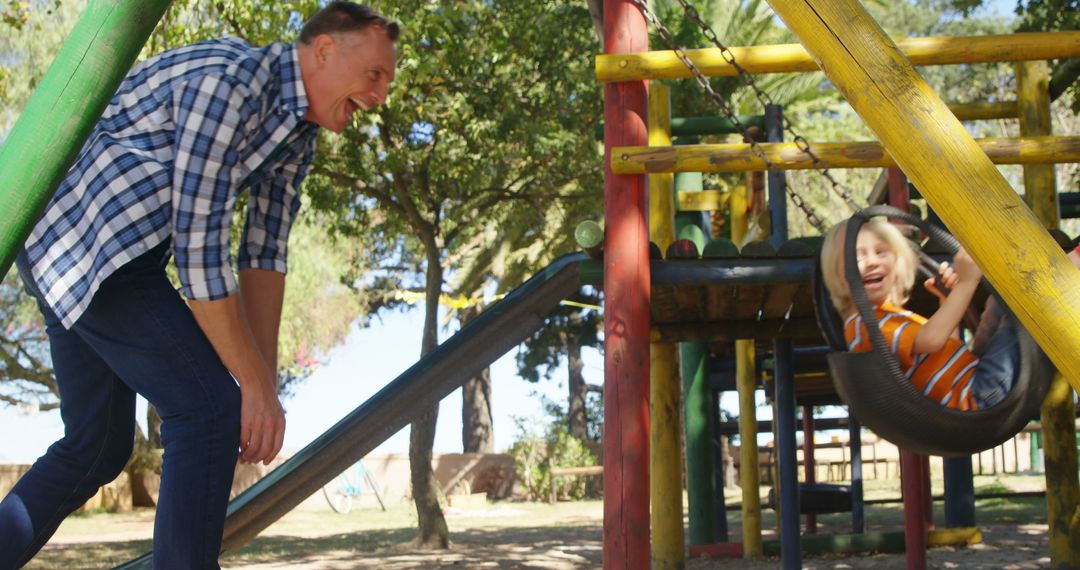 Grandfather pushing grandson on tire swing in playground - Free Images, Stock Photos and Pictures on Pikwizard.com