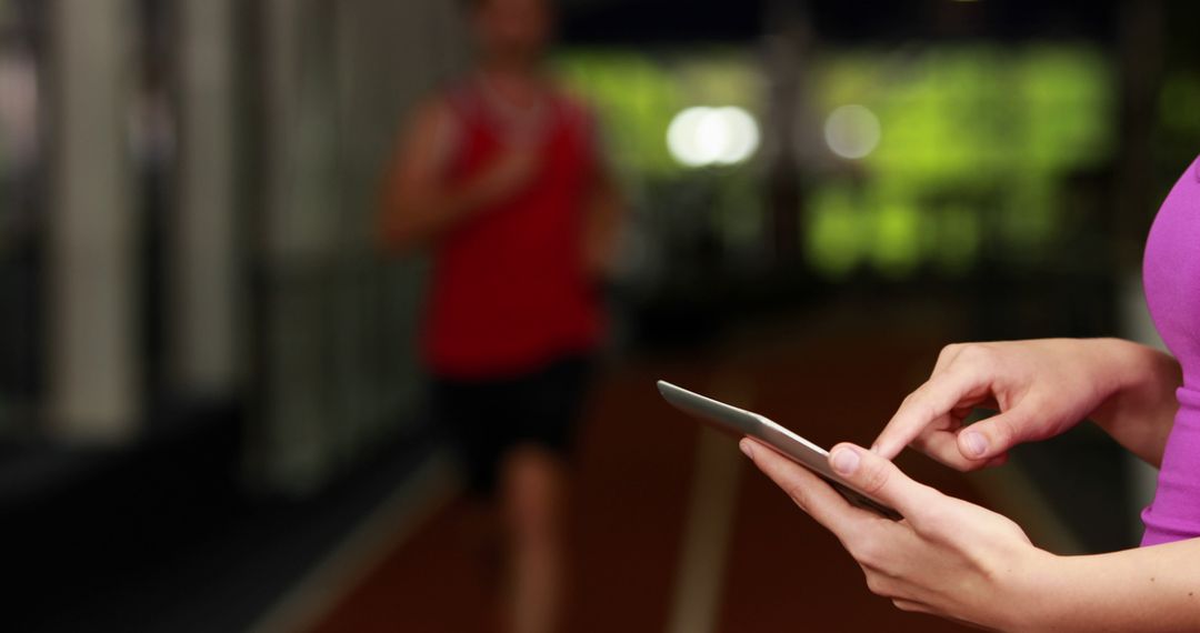 Young Woman Using Tablet at Gym with Blurred Running Track Background - Free Images, Stock Photos and Pictures on Pikwizard.com