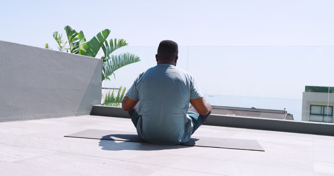 Man Practicing Meditation on Rooftop with Ocean View