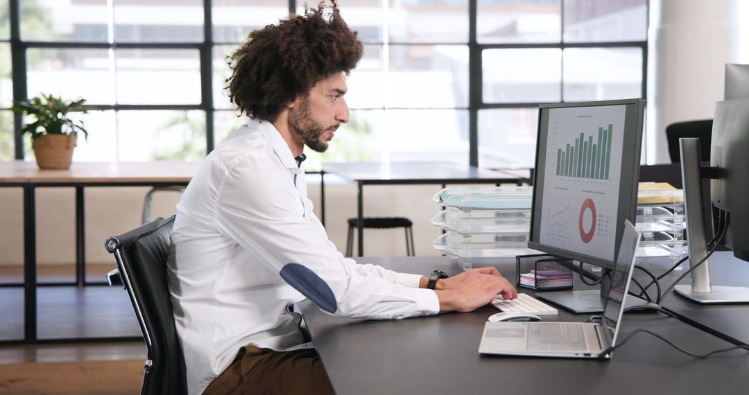 Focused Business Professional Analyzing Data on Dual Monitors