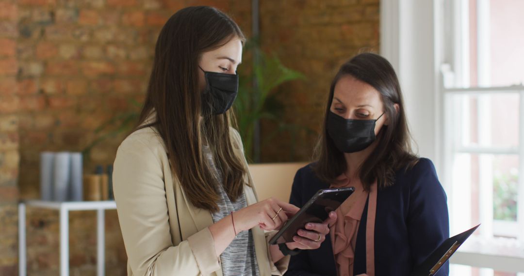 Women in Business Meeting Using Smartphone and Tablet with Masks - Free Images, Stock Photos and Pictures on Pikwizard.com