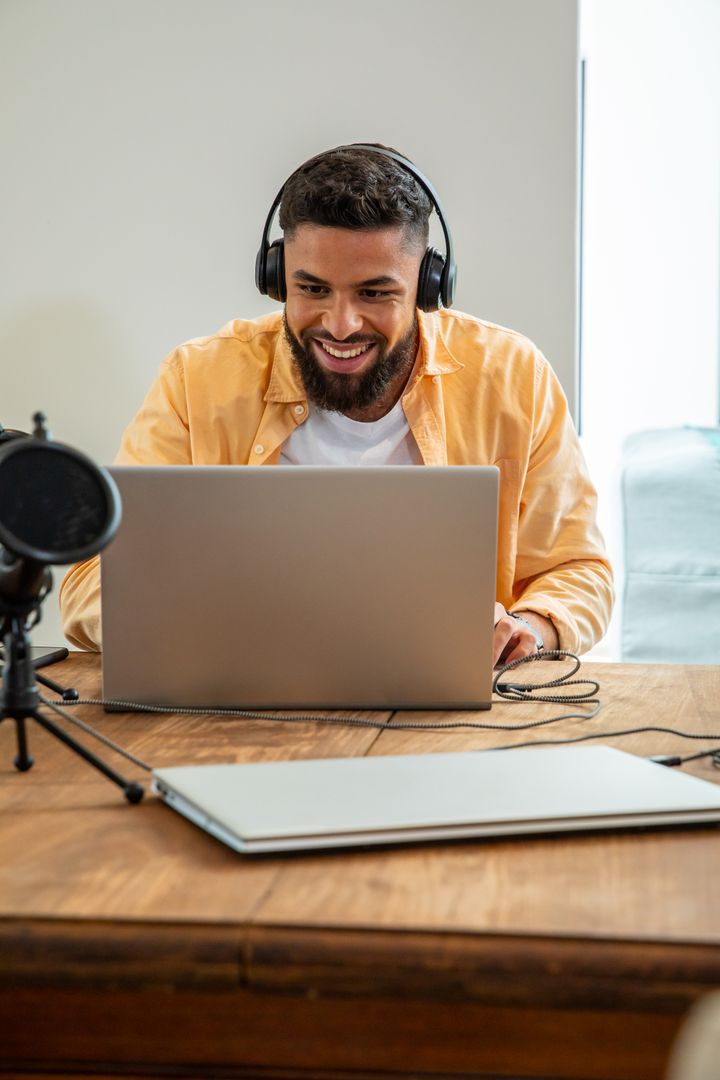 Smiling Man Using Laptop with Microphone Expressing Creativity