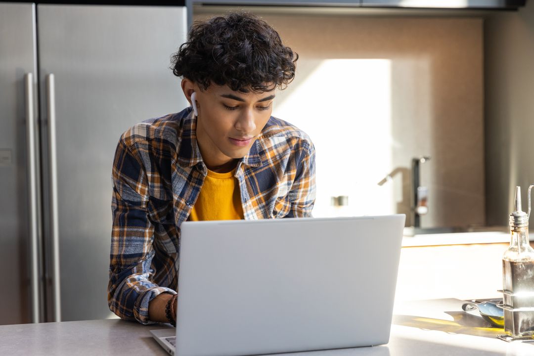 Young Man Engaged in Remote Work from Bright Home Kitchen