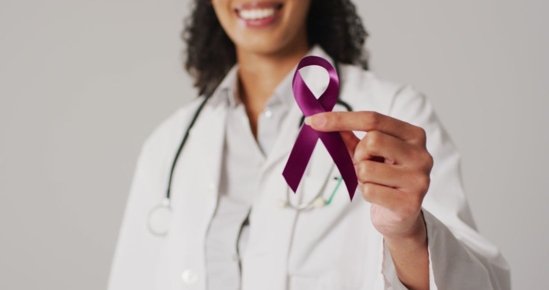 Image of smiling biracial female doctor holding purple pancreatic cancer ribbon - Free Images, Stock Photos and Pictures on Pikwizard.com