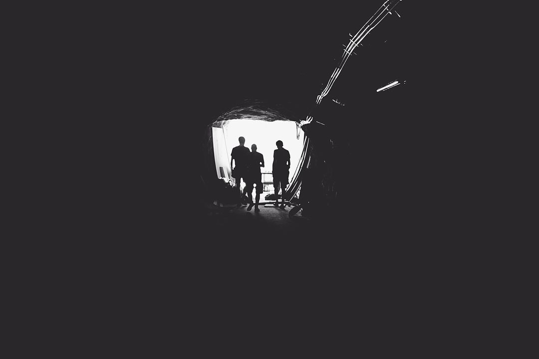 Silhouetted Figures at Tunnel Exit Into Bright Light