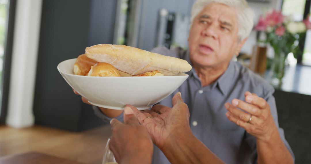 Senior Man Receiving Bread Bowl from Hands in Kitchen - Free Images, Stock Photos and Pictures on Pikwizard.com