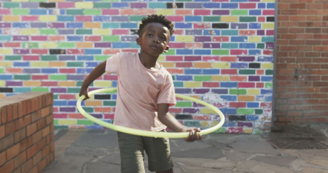 Playful Child Spinning Hula Hoop in Multicolored Urban Courtyard