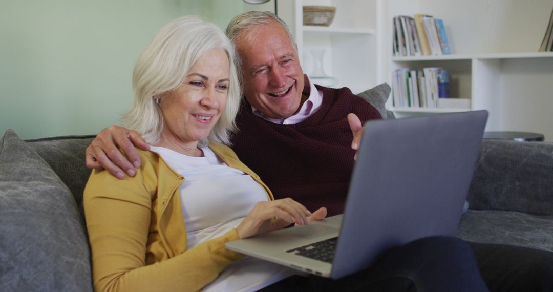 Happy Senior Couple Relaxing on Sofa Enjoying Laptop