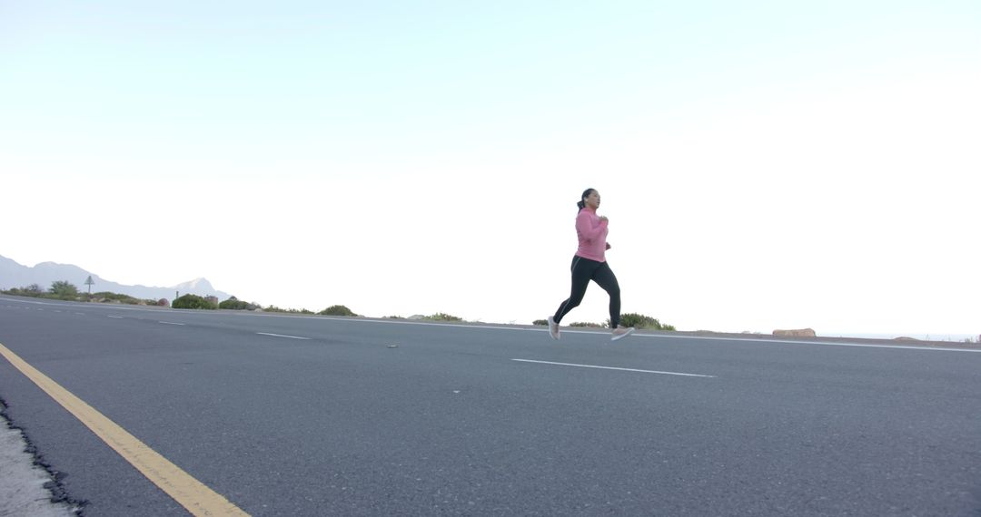 Woman Running on Open Road with Mountain Landscape
