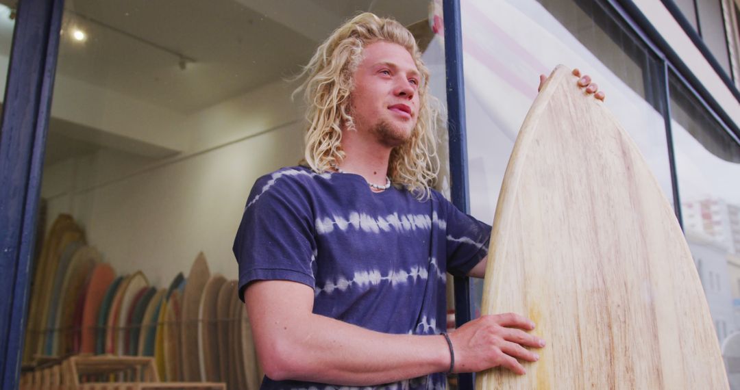 Young Man Holding Surfboard at Surf Shop Display - Free Images, Stock Photos and Pictures on Pikwizard.com