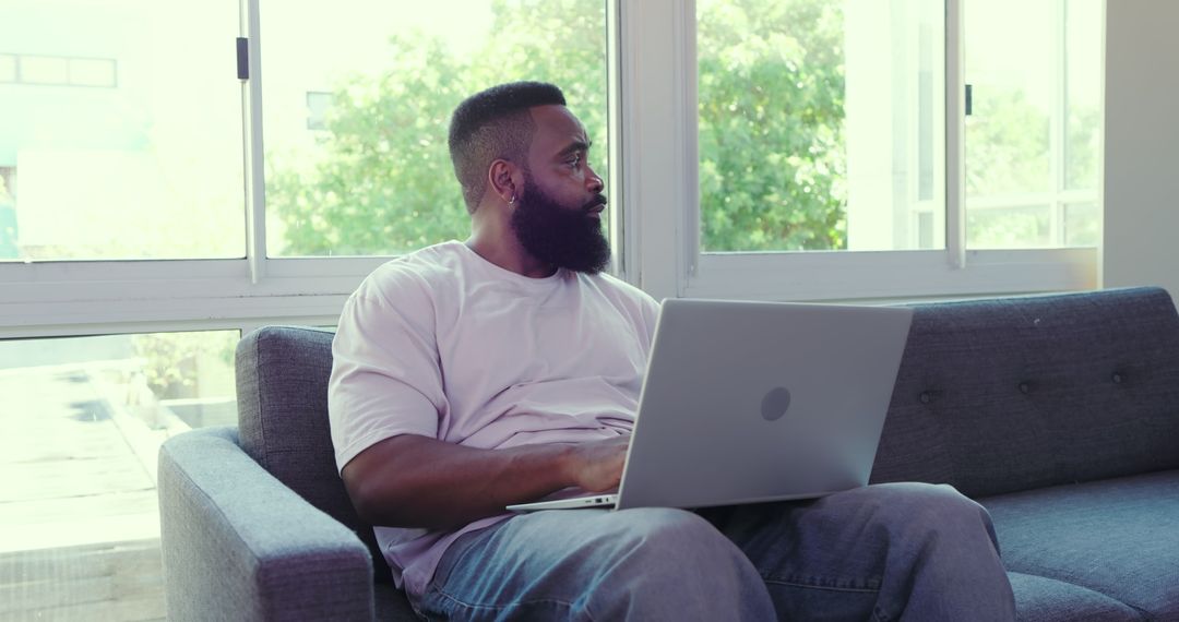 Man with Laptop Relaxing by Window in Modern Living Room