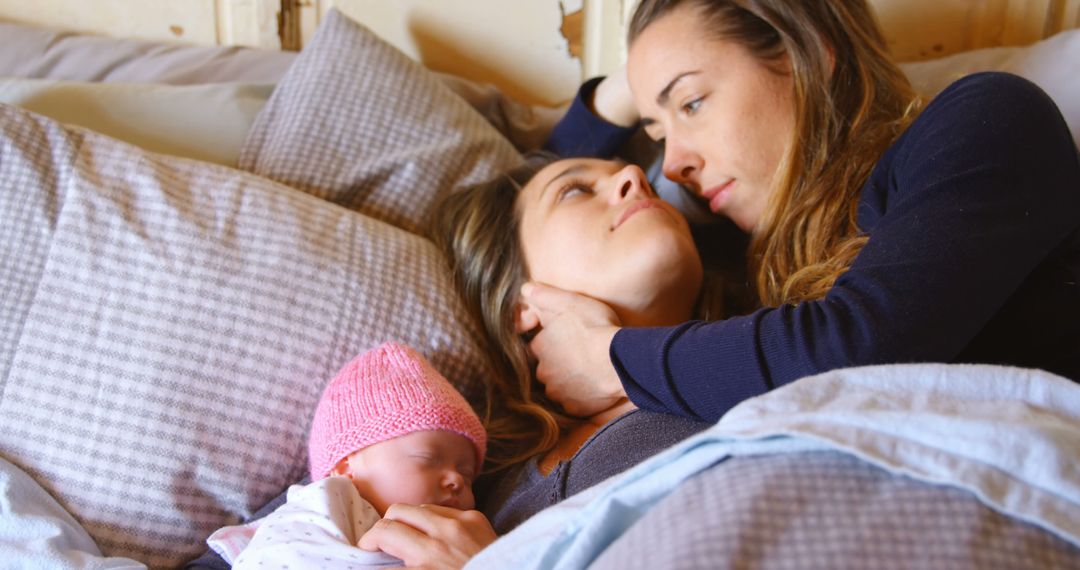 Tender Moment Between Mother and Partner with Newborn Baby in Bed - Free Images, Stock Photos and Pictures on Pikwizard.com