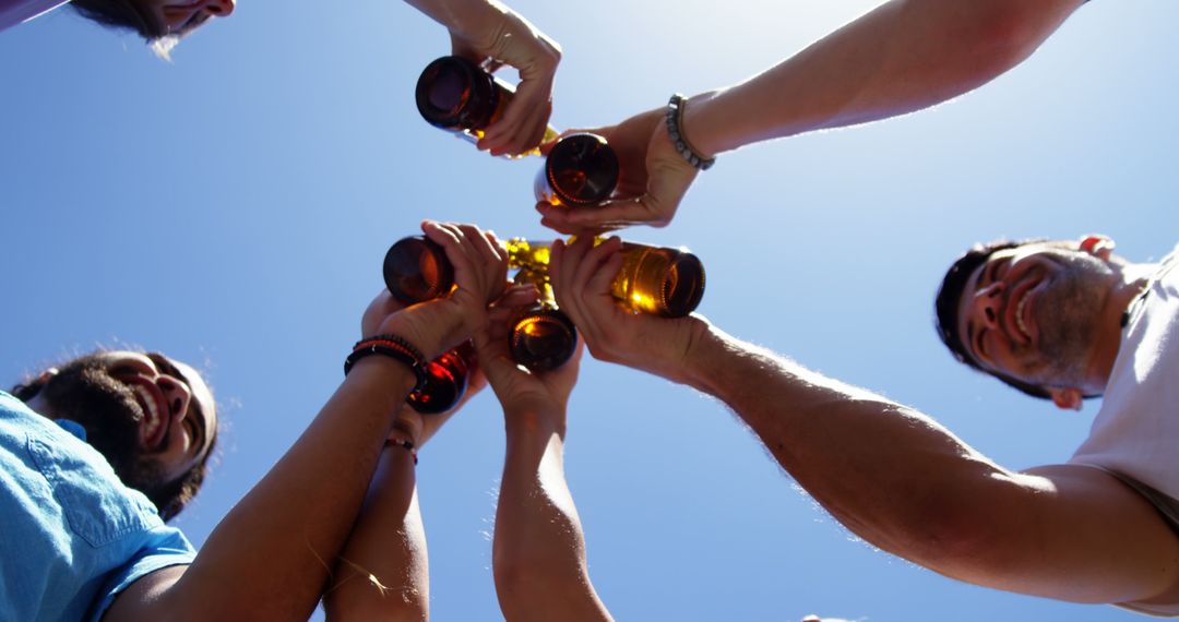 Friends Toasting with Bottles Against Clear Blue Sky - Free Images, Stock Photos and Pictures on Pikwizard.com