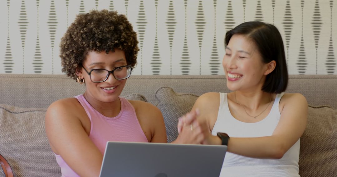 Diverse Friends Smiling While Using Laptop on Couch