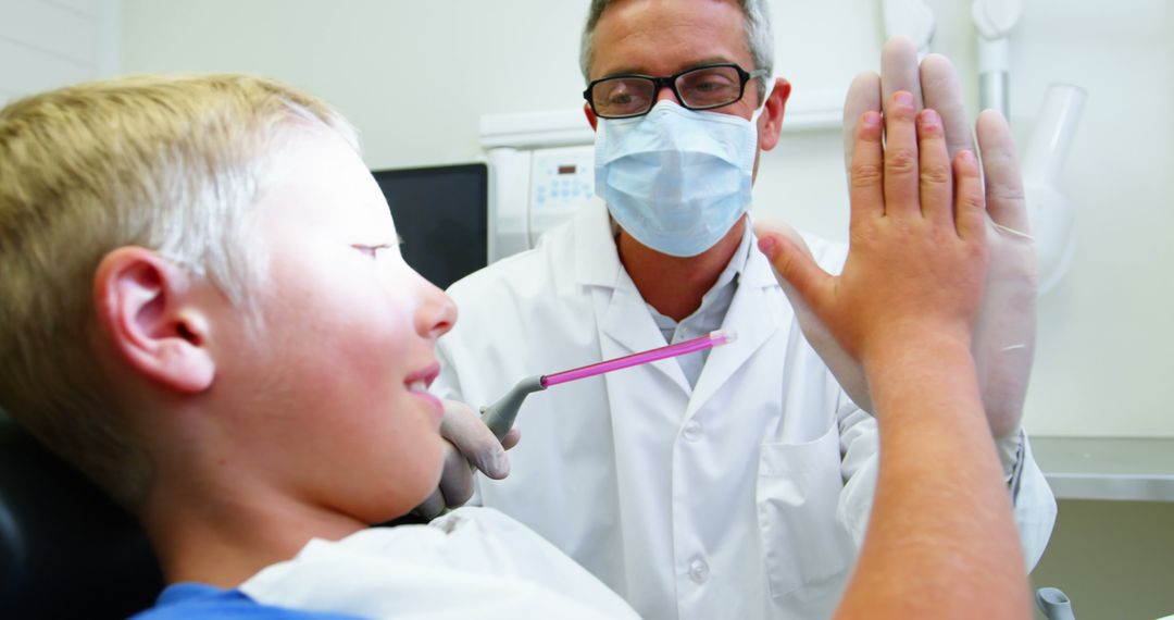 Dentist High-Fiving Young Boy During Dental Checkup - Free Images, Stock Photos and Pictures on Pikwizard.com