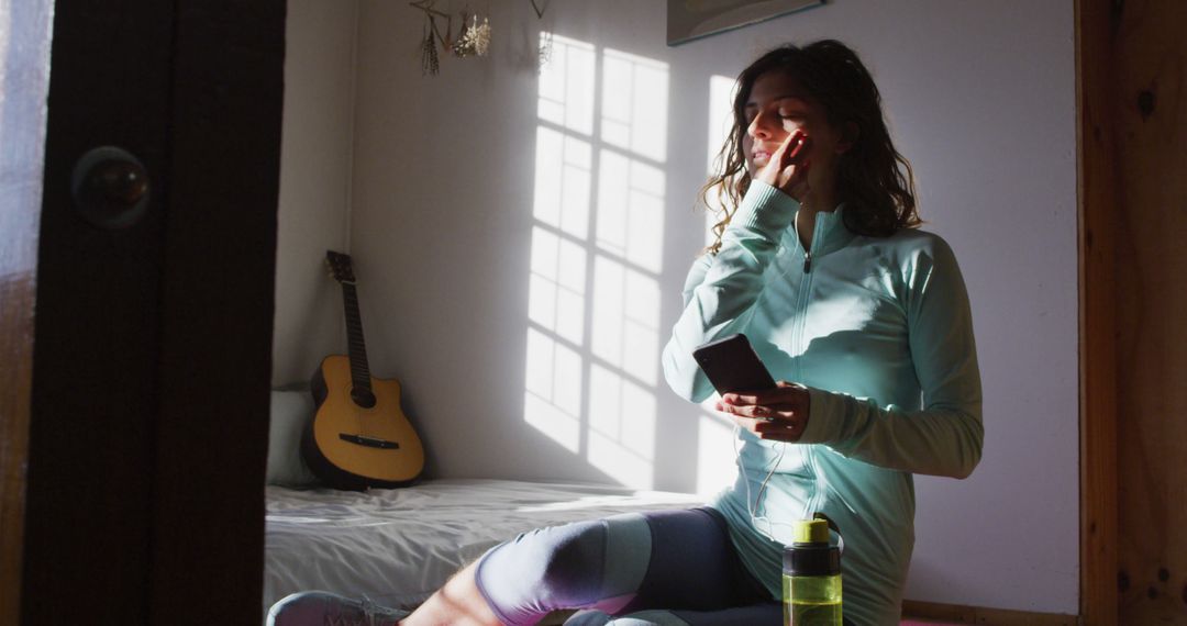 Woman Prepares for Workout Holding Smartphone in Sunny Room - Free Images, Stock Photos and Pictures on Pikwizard.com