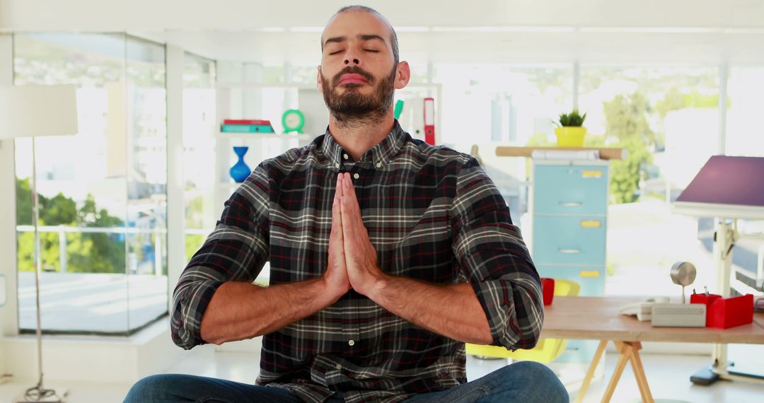 A man finds a peaceful moment to meditate in his bright office. - Free Images, Stock Photos and Pictures on Pikwizard.com