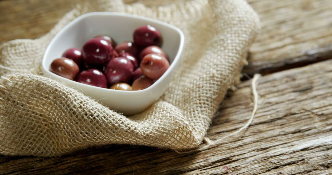 Assortment of Olives in White Bowl on Burlap Cloth and Wooden Table - Free Images, Stock Photos and Pictures on Pikwizard.com