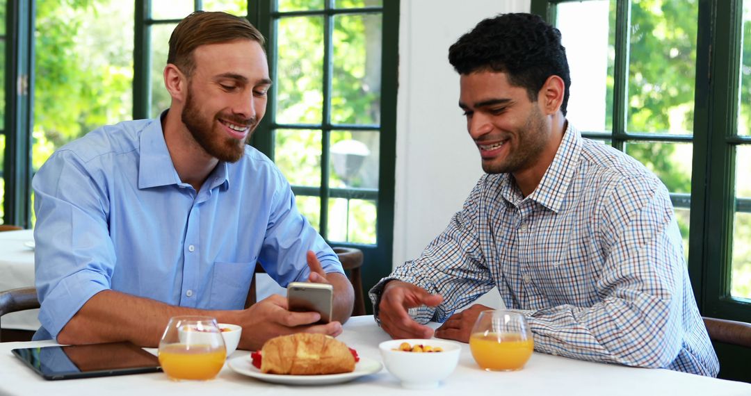 Two Friends Enjoying Breakfast and Smartphone Conversation