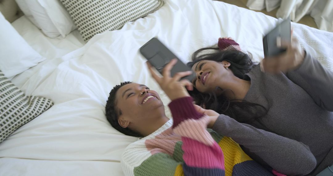 Friends Relaxing Together on Bed with Smartphones