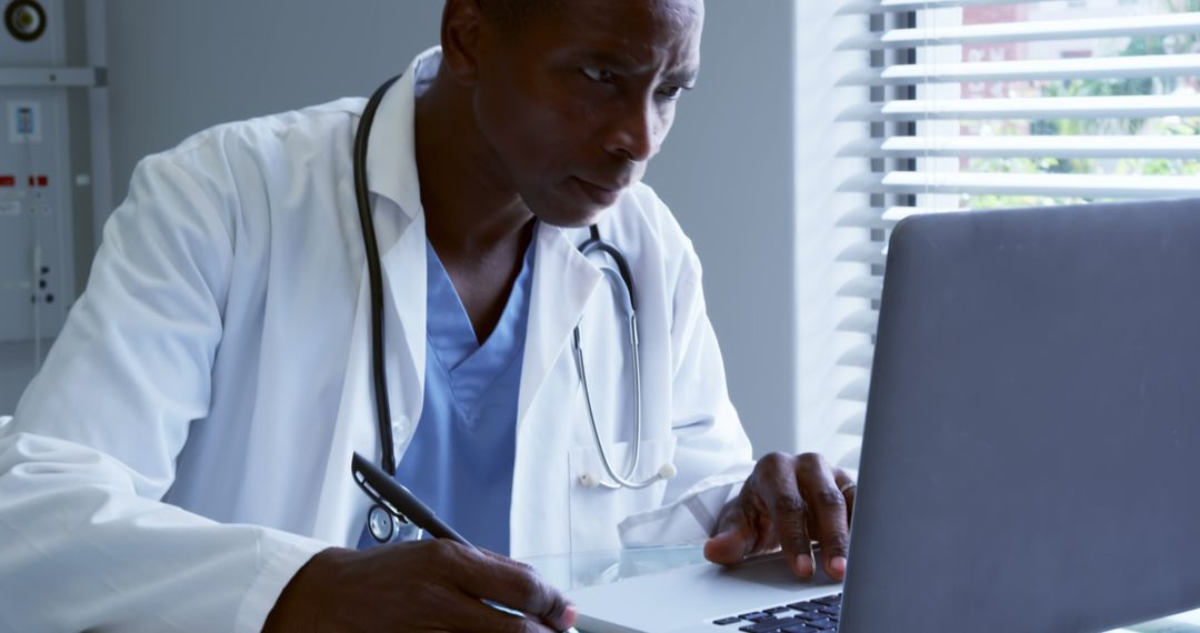 Focused African American Doctor Working on Laptop in Hospital Office - Free Images, Stock Photos and Pictures on Pikwizard.com