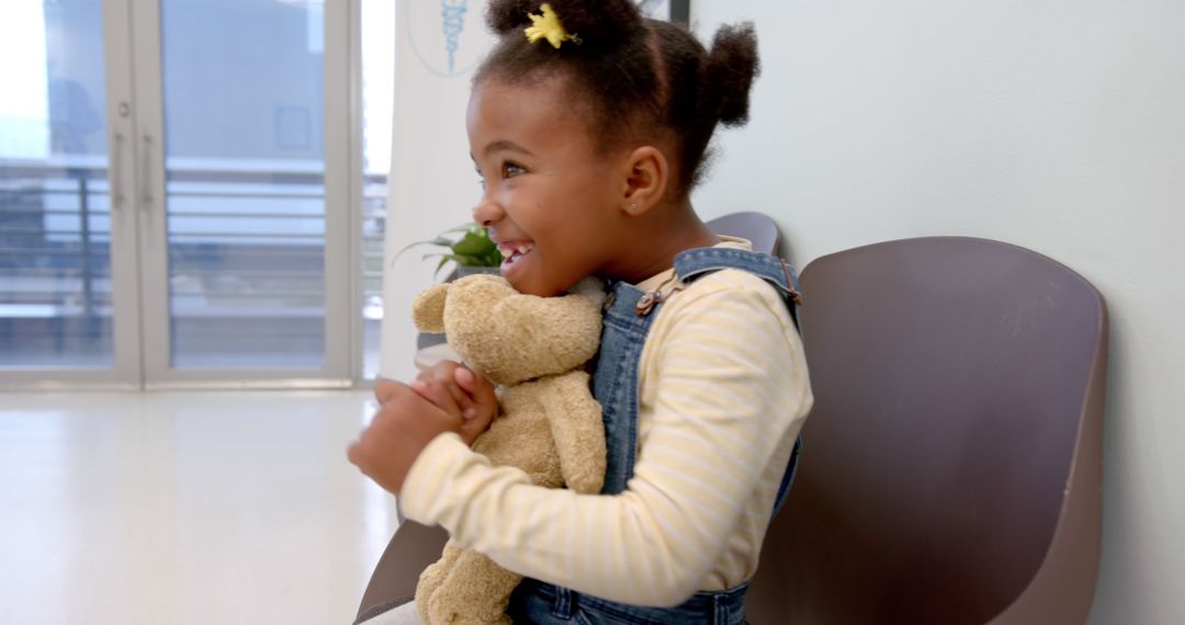 Smiling Young Girl Hugging Teddy Bear in Modern Waiting Room - Free Images, Stock Photos and Pictures on Pikwizard.com