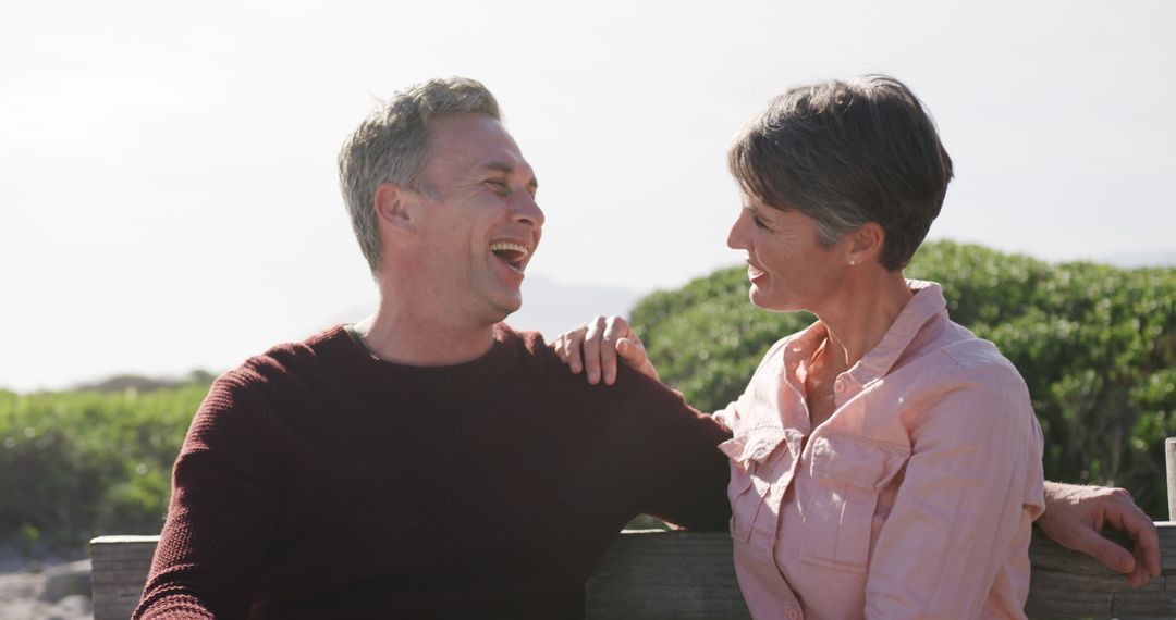 Senior Couple Laughing on Beach Bench