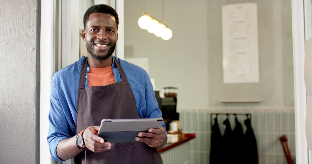 Smiling Barista Holding Tablet Device in Modern Cafe Space