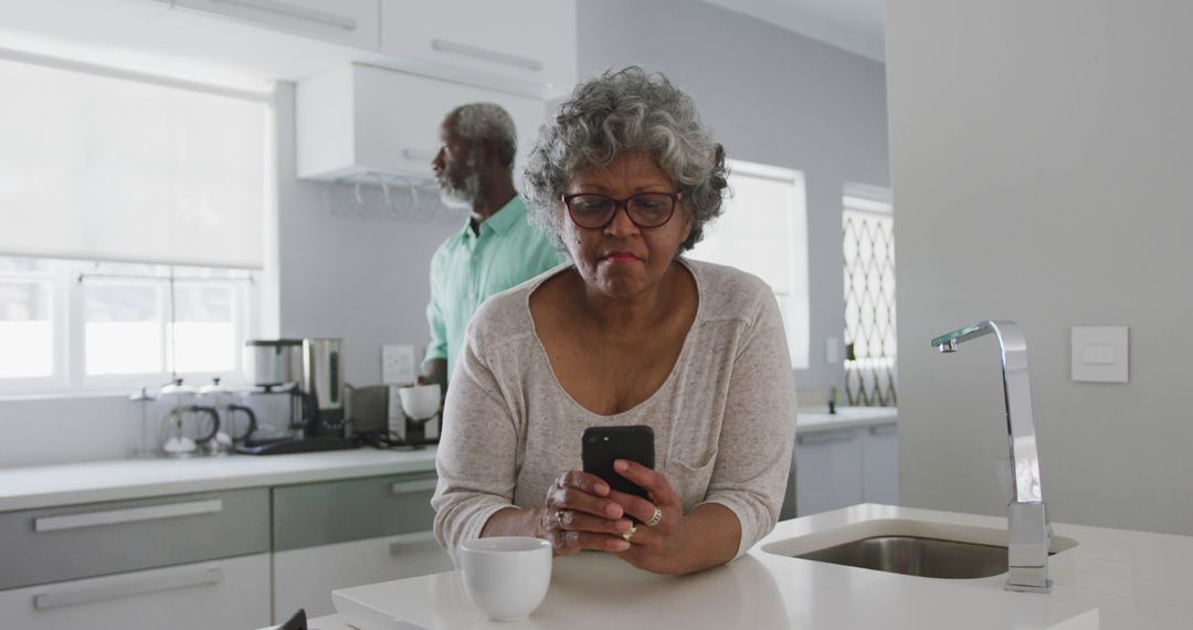 Elderly Woman Using Smartphone in Modern Kitchen - Free Images, Stock Photos and Pictures on Pikwizard.com