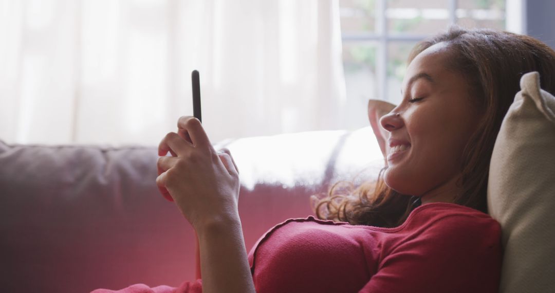 Young Woman Reclining on Couch Using Smartphone in Relaxed Setting - Free Images, Stock Photos and Pictures on Pikwizard.com