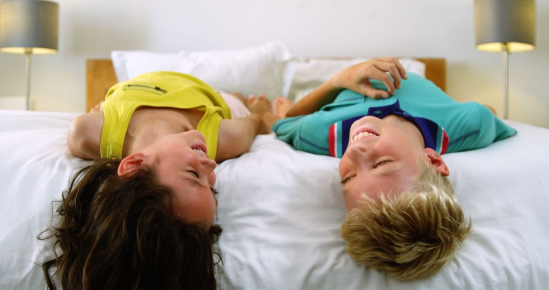 Children Laughing on Bed in Playful Moment - Free Images, Stock Photos and Pictures on Pikwizard.com