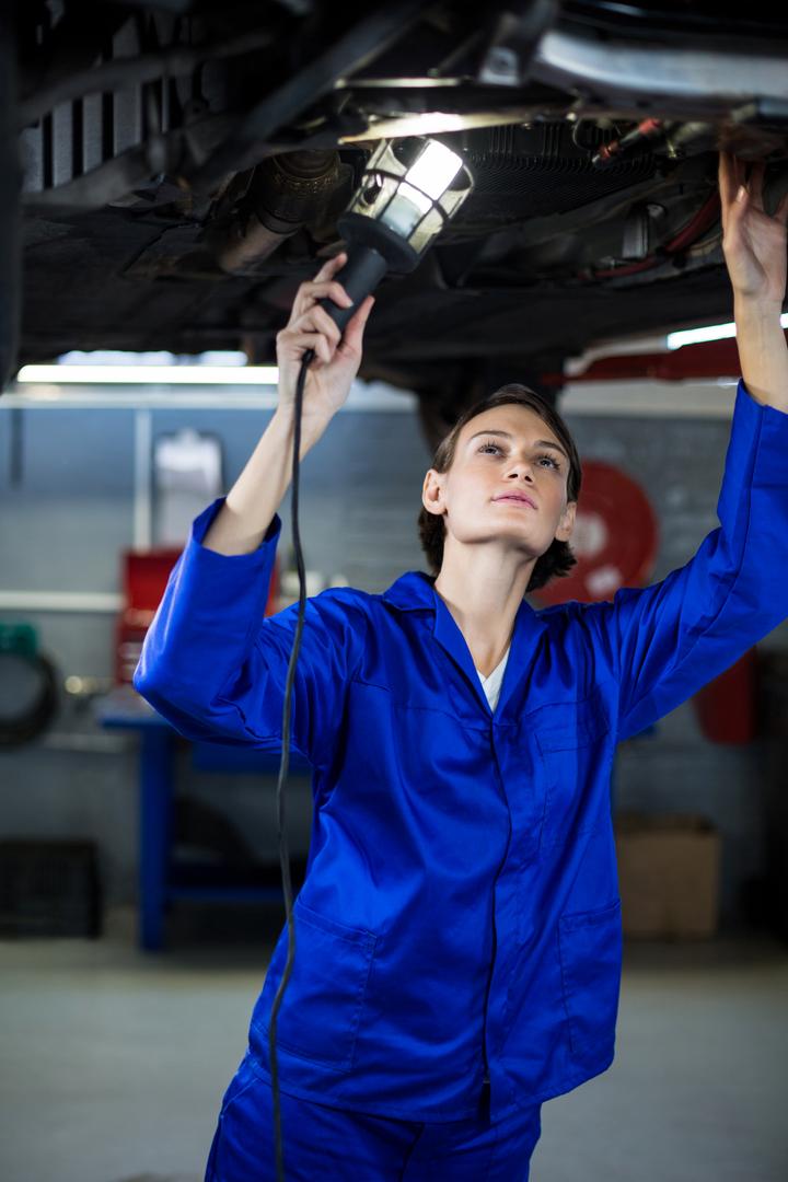 Female Mechanic Examining Car with Lamp in Repair Garage - Free Images, Stock Photos and Pictures on Pikwizard.com