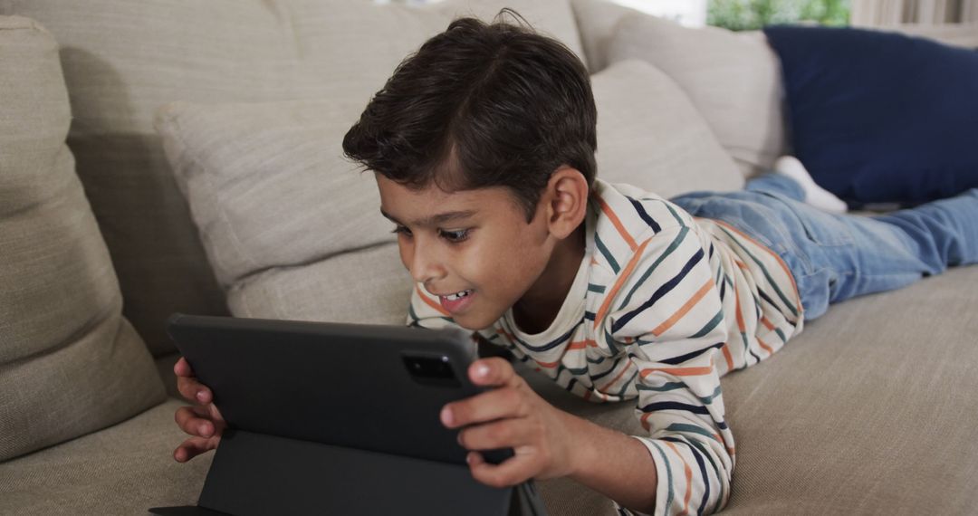 Happy Boy Using Tablet on Sofa at Home