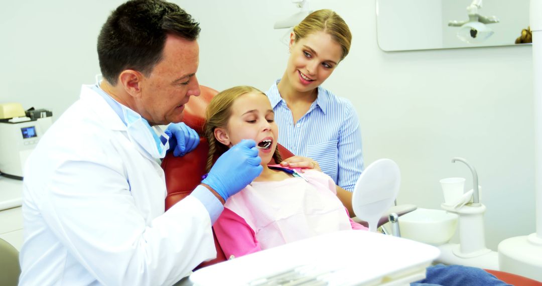 Dentist Examining Young Girl's Teeth with Mother Watching in Modern Clinic - Free Images, Stock Photos and Pictures on Pikwizard.com