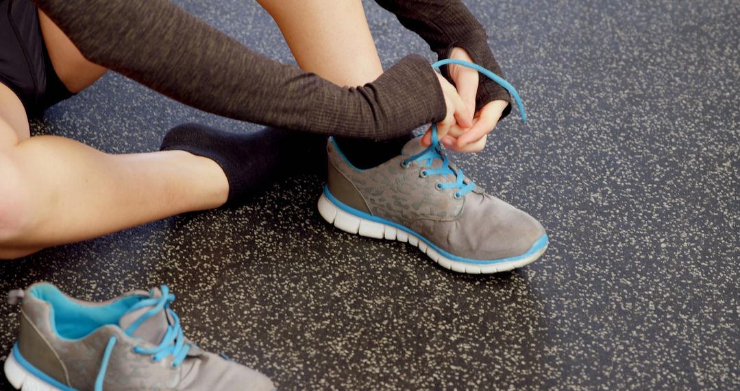 Active Woman Tying Shoelaces in Gym for Workout Preparation