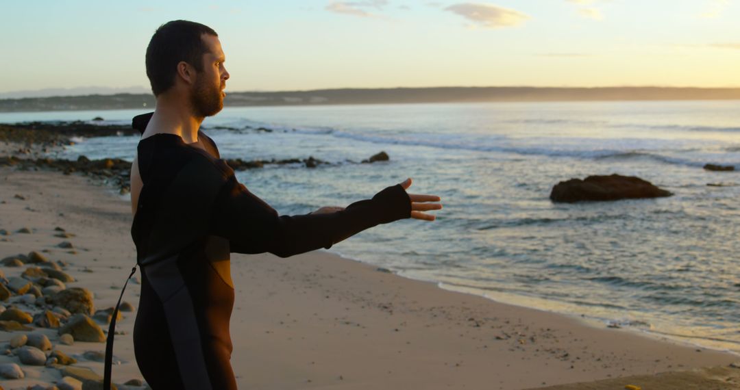 Surfer Stretching on Beach at Sunrise in Wetsuit - Free Images, Stock Photos and Pictures on Pikwizard.com