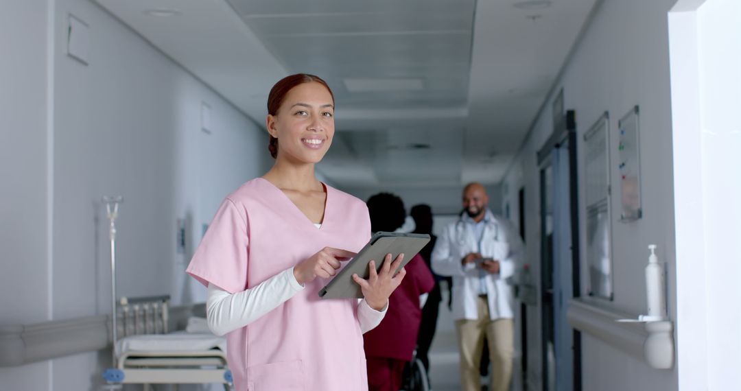 Smiling Nurse in Hospital Corridor Using Tablet - Free Images, Stock Photos and Pictures on Pikwizard.com