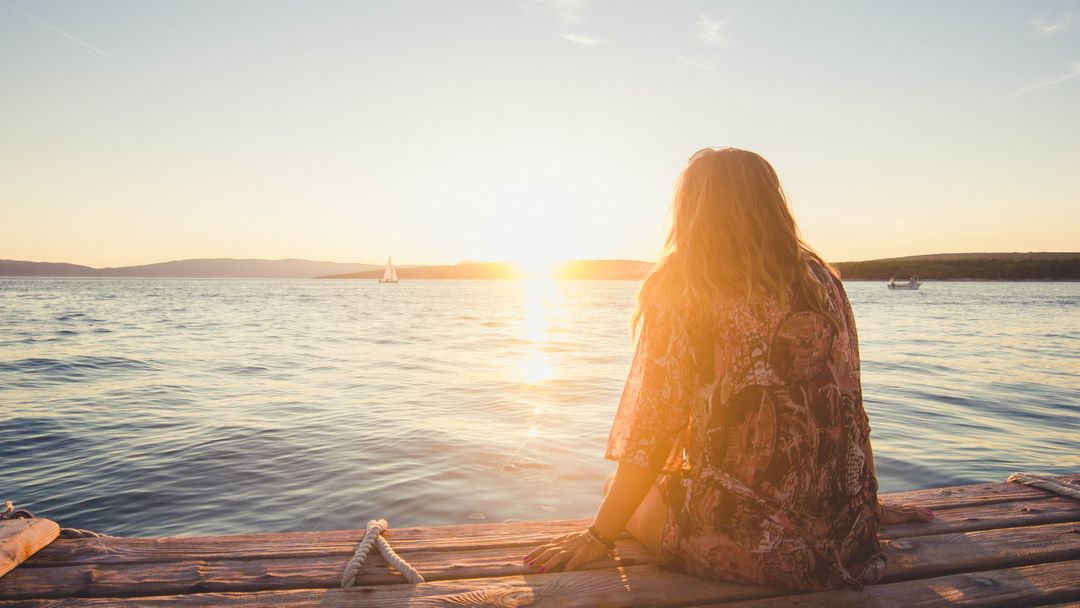 Woman Watching Sunset by Lake on Wooden Deck - Free Images, Stock Photos and Pictures on Pikwizard.com