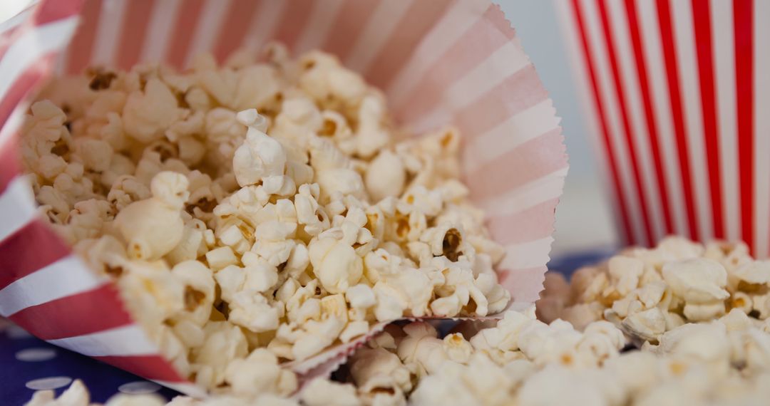 Tasty Popcorn Overflowing from Striped Box on Polka Dotted Surface - Free Images, Stock Photos and Pictures on Pikwizard.com