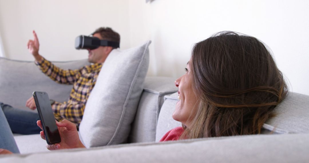 Couple Enjoying Virtual Reality and Smartphone on Sofa - Free Images, Stock Photos and Pictures on Pikwizard.com