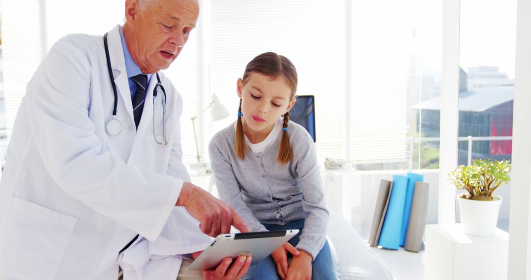 Senior Doctor Using Tablet to Explain Treatment to Young Girl in Bright Clinic - Free Images, Stock Photos and Pictures on Pikwizard.com