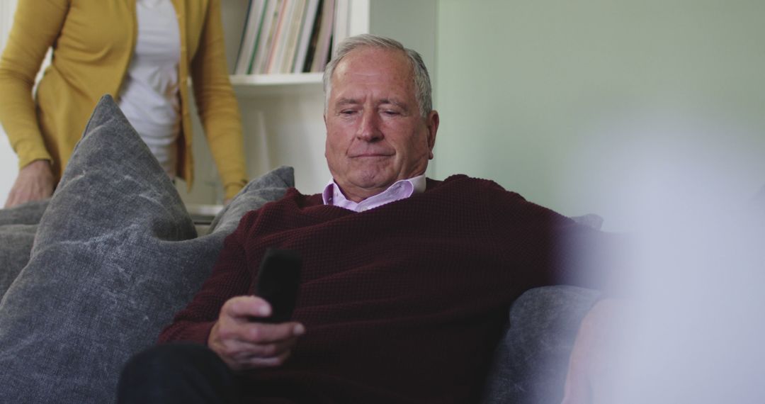 Relaxed Senior Man Holding TV Remote While Sitting on Couch at Home - Free Images, Stock Photos and Pictures on Pikwizard.com