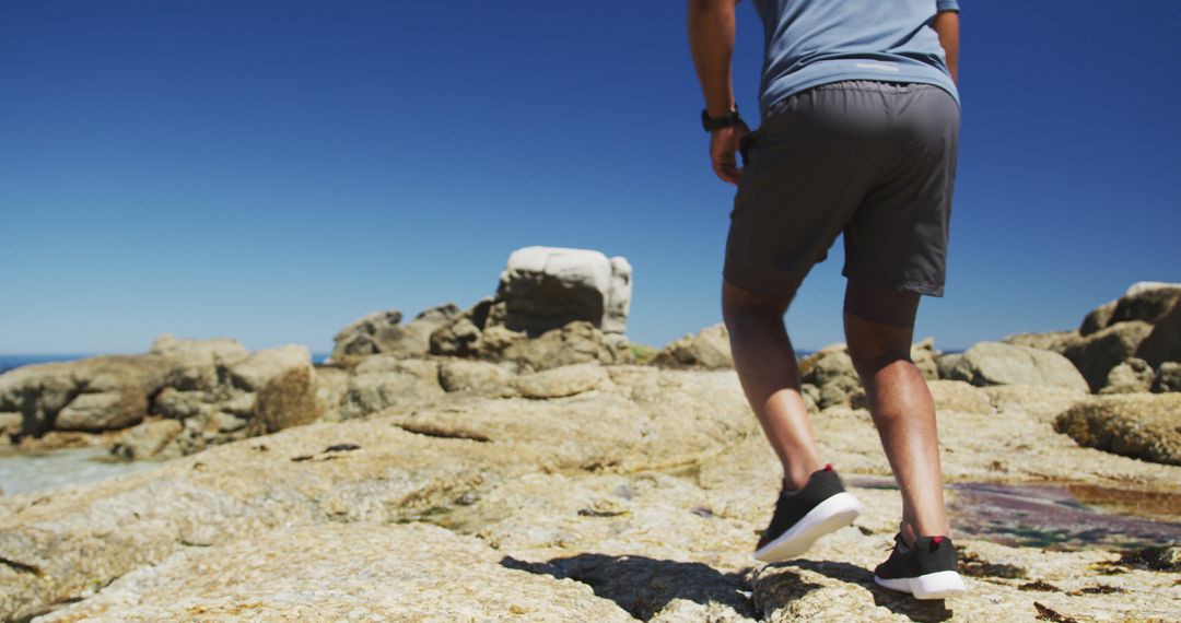 Man Hiking on Rocky Seaside in Shorts and Sneakers - Free Images, Stock Photos and Pictures on Pikwizard.com