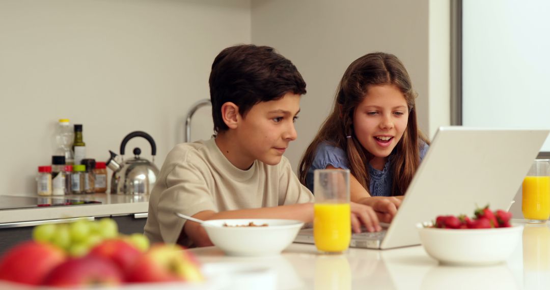 Young Siblings Enjoying Breakfast Together While Using Laptop in Kitchen - Free Images, Stock Photos and Pictures on Pikwizard.com